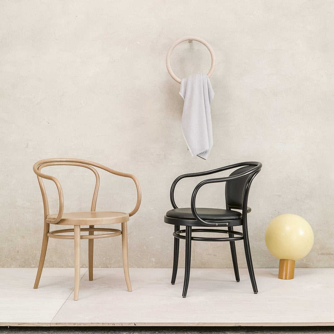 "Natural wood and black finish chairs with curved patterns, set against a minimalist backdrop."