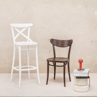 Two chairs: a white cross-back barstool and a dark brown traditional chair, styled against a neutral background.