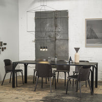 Modern black dining table with dark chairs, set against a rustic wood floor and minimalist gray walls for a sleek look.