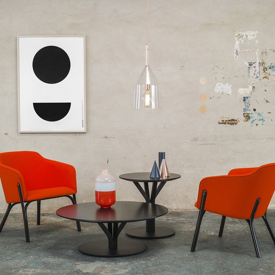 Vibrant orange chairs with black and white patterns, modern round tables with sleek designs against a textured wall.