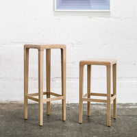 Light wood bar stools with a natural finish, featuring clean lines and a simple, modern design.