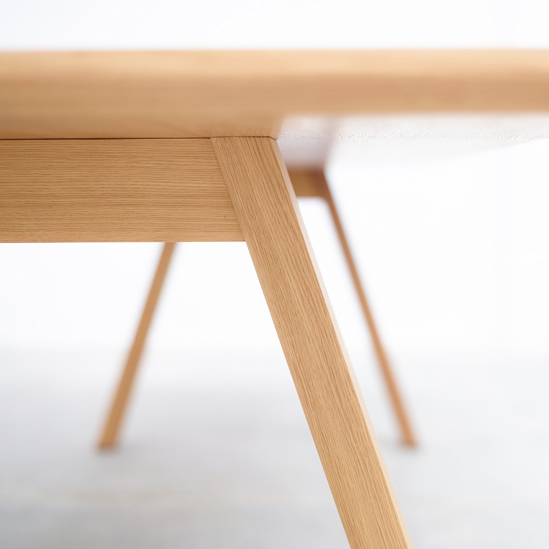 Light natural wood table with clean lines and minimalistic design, showcasing a smooth surface and tapered legs.