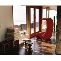 Vibrant red modern chair with smooth curves, complemented by neutral-toned wooden floors and natural light.