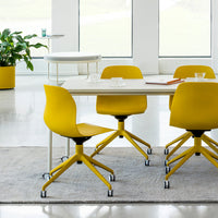 Bright yellow swivel chairs around a modern white table, set on a textured gray rug in a bright, airy space.