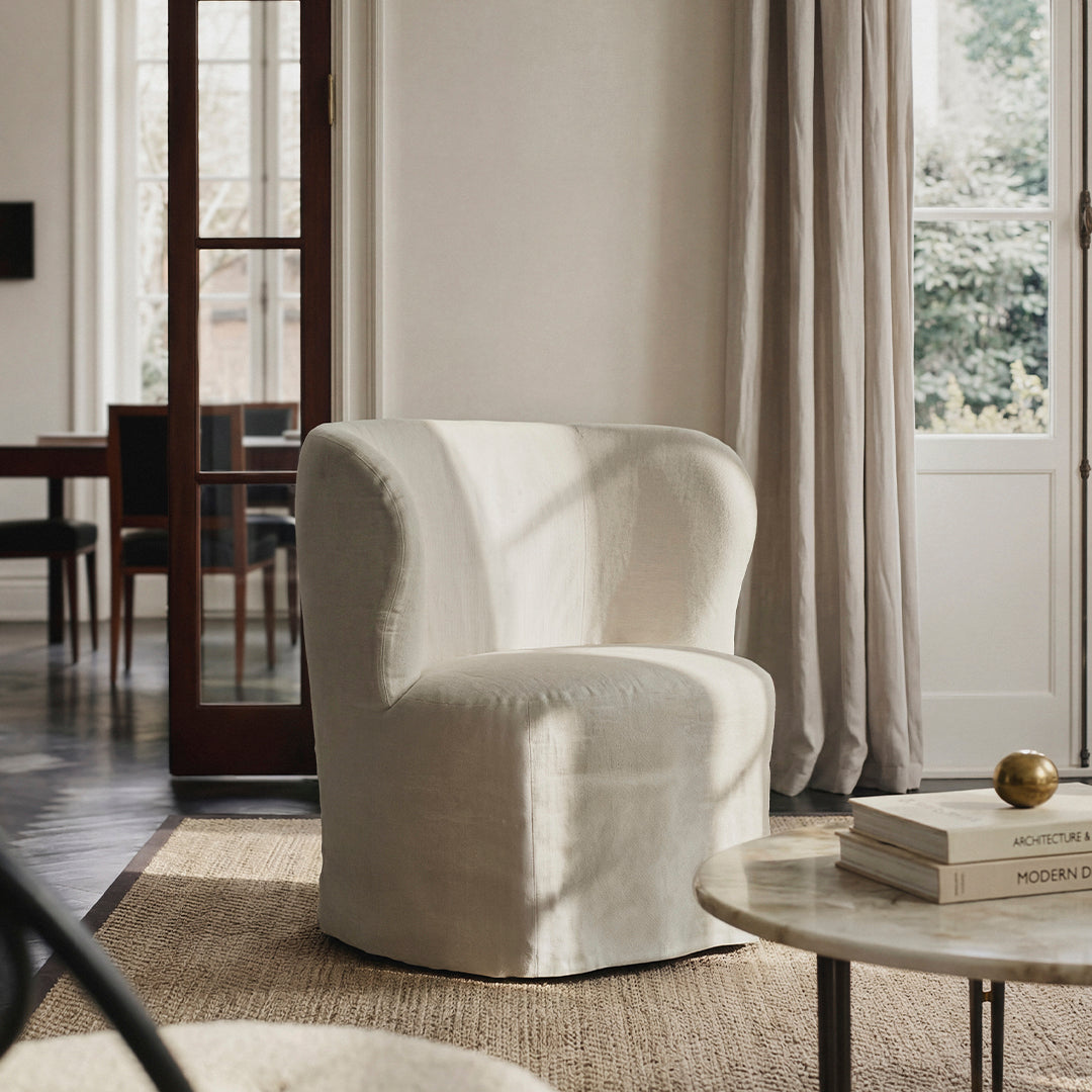 Cream-colored upholstered armchair with a rounded silhouette, soft texture, and subtle stitching detailing.