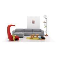 Contemporary living room with a gray sofa, vibrant red accent chair, yellow circular rug, and playful decor elements.