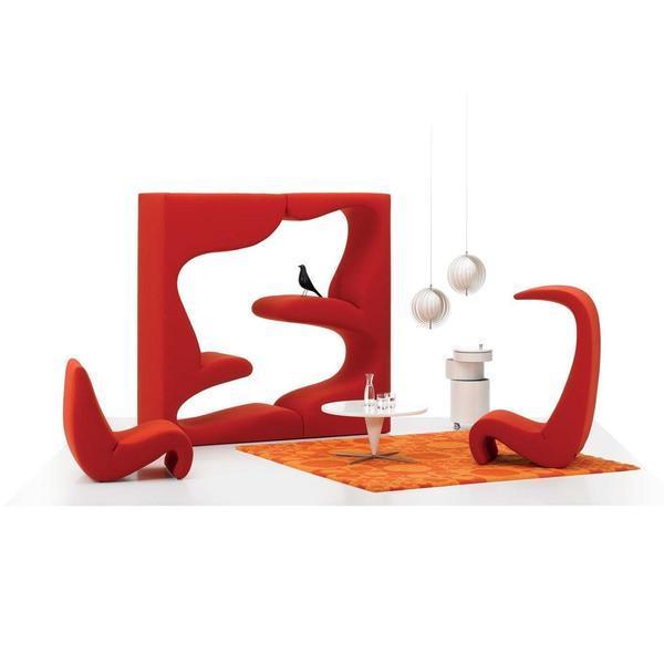 Stylish modern furniture in vibrant red with organic shapes and abstract patterns, complemented by an orange rug.