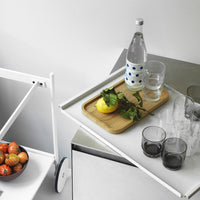 White tray with blue polka dots, bamboo, lemon, mint, and black glasses on a sleek stainless steel surface.
