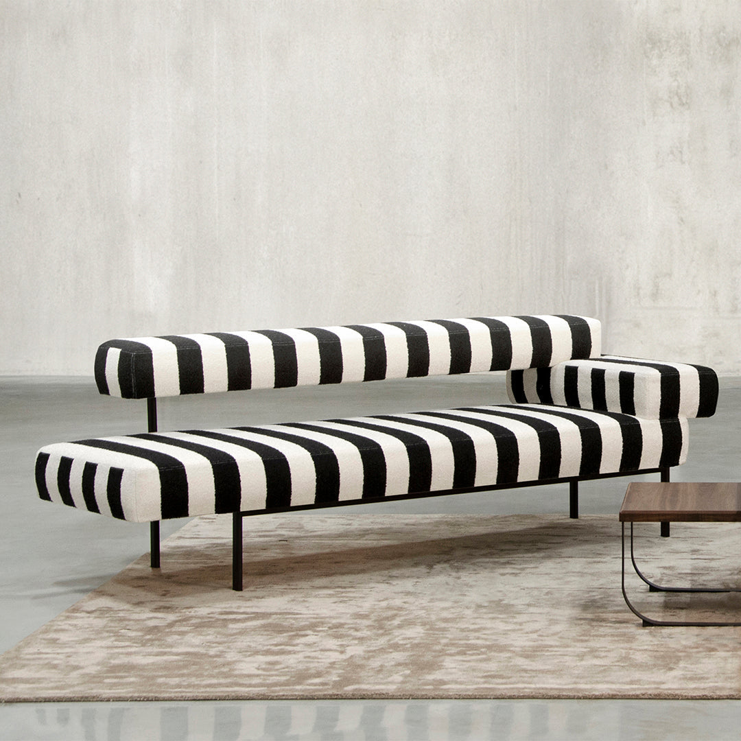 Black and white striped sofa with modern design, featuring bold patterns against a neutral background.