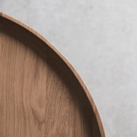 Natural wooden surface with light brown tones and a smooth, curved edge against a gray background.