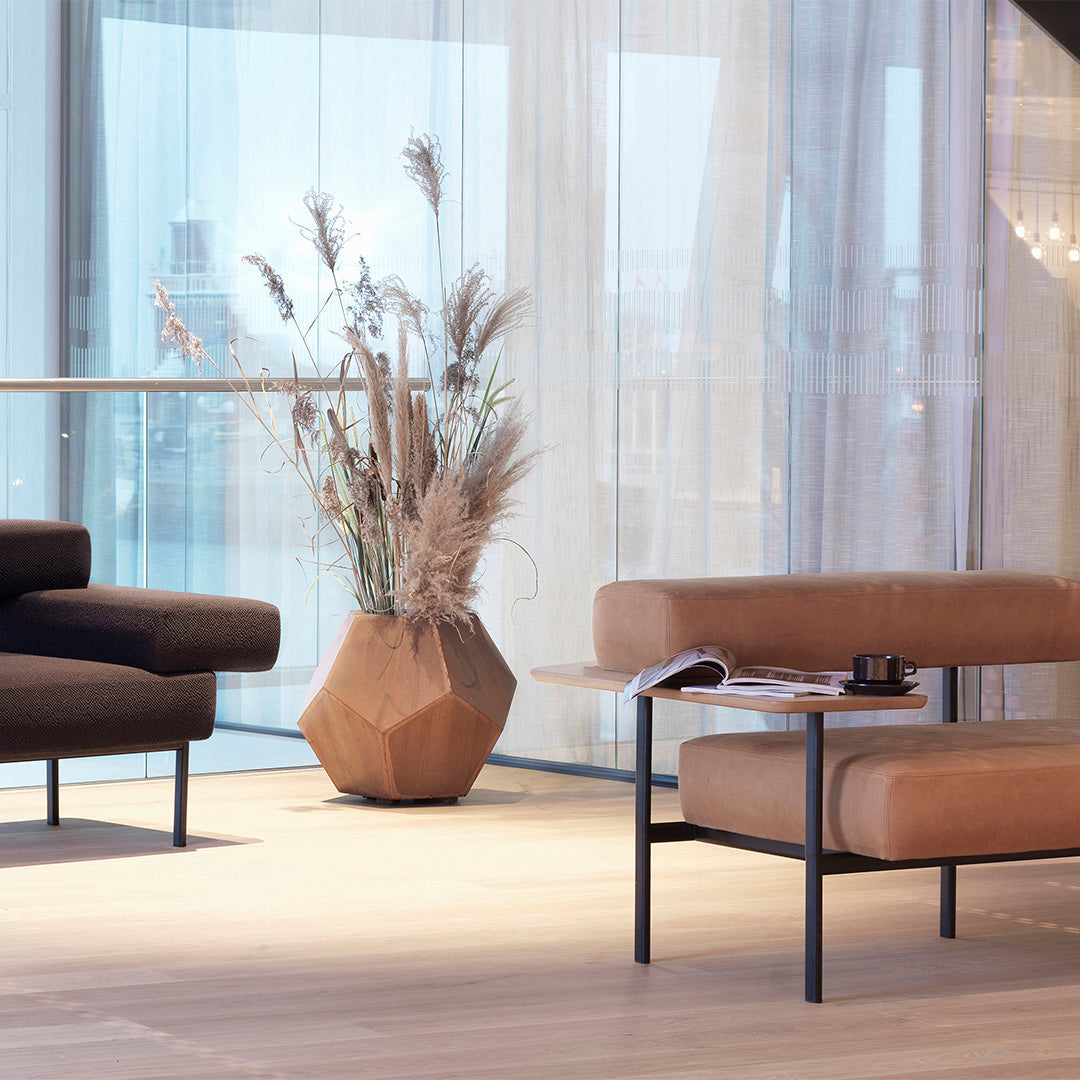 Brown textured couch, tan cushions, geometric clay planter, beige curtains, and light wood flooring create a warm palette.