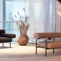 Brown textured couch, tan cushions, geometric clay planter, beige curtains, and light wood flooring create a warm palette.