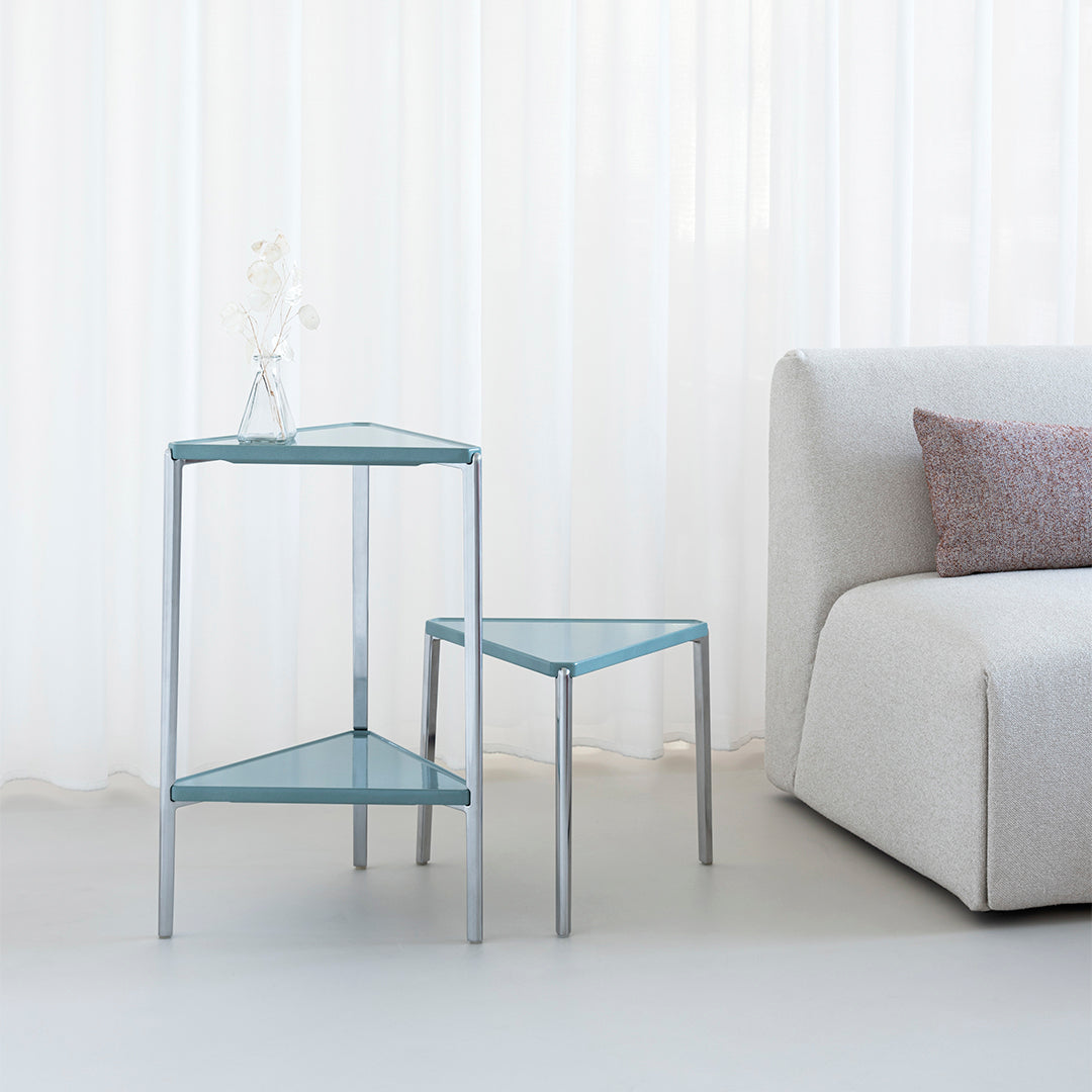 Aqua blue geometric side tables with a sleek chrome frame against a soft, neutral backdrop.