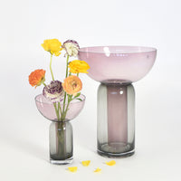 "Transparent pink and gray glass vases with floral accents, showcasing a smooth gradient and elegant curves."