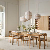 Scandinavian dining setup featuring light wood, white and cream tones, with striped pendant lights and neutral accents.
