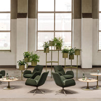 Elegant green armchairs with neutral-toned tables and planters, creating a calming, modern interior vibe.