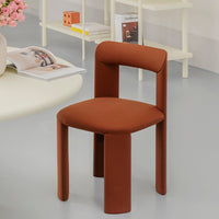 Rust-colored modern chair with smooth curves and a soft fabric finish, complementing a minimalist interior design.