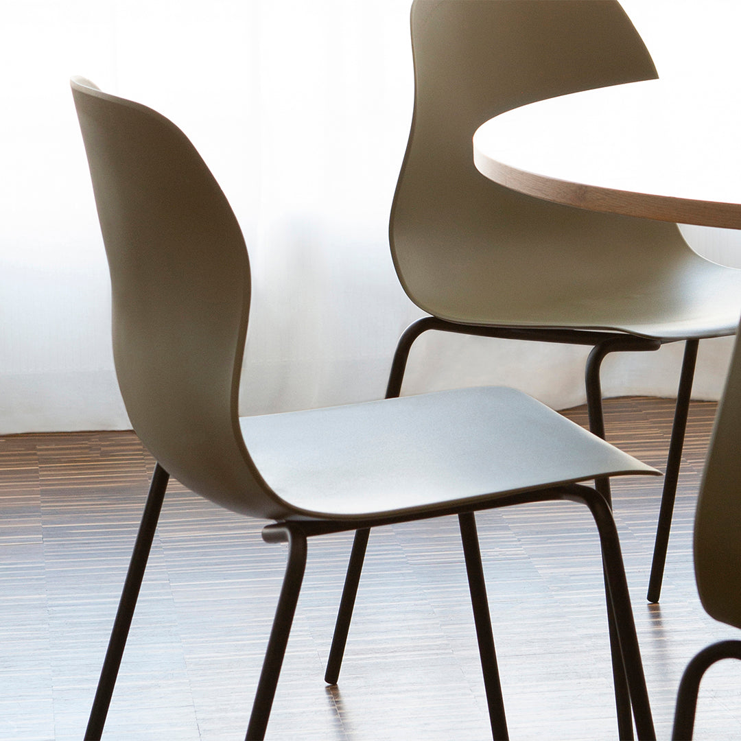 Modern olive green chair with a smooth matte finish and black metal legs, set against a light and airy backdrop.