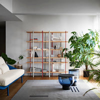 Modern bookshelf with light wood shelves, red and white accents, complemented by blue and gray furnishings.