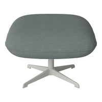 Soft grey upholstery on a round, padded ottoman with a sleek white base, perfect for modern decor.