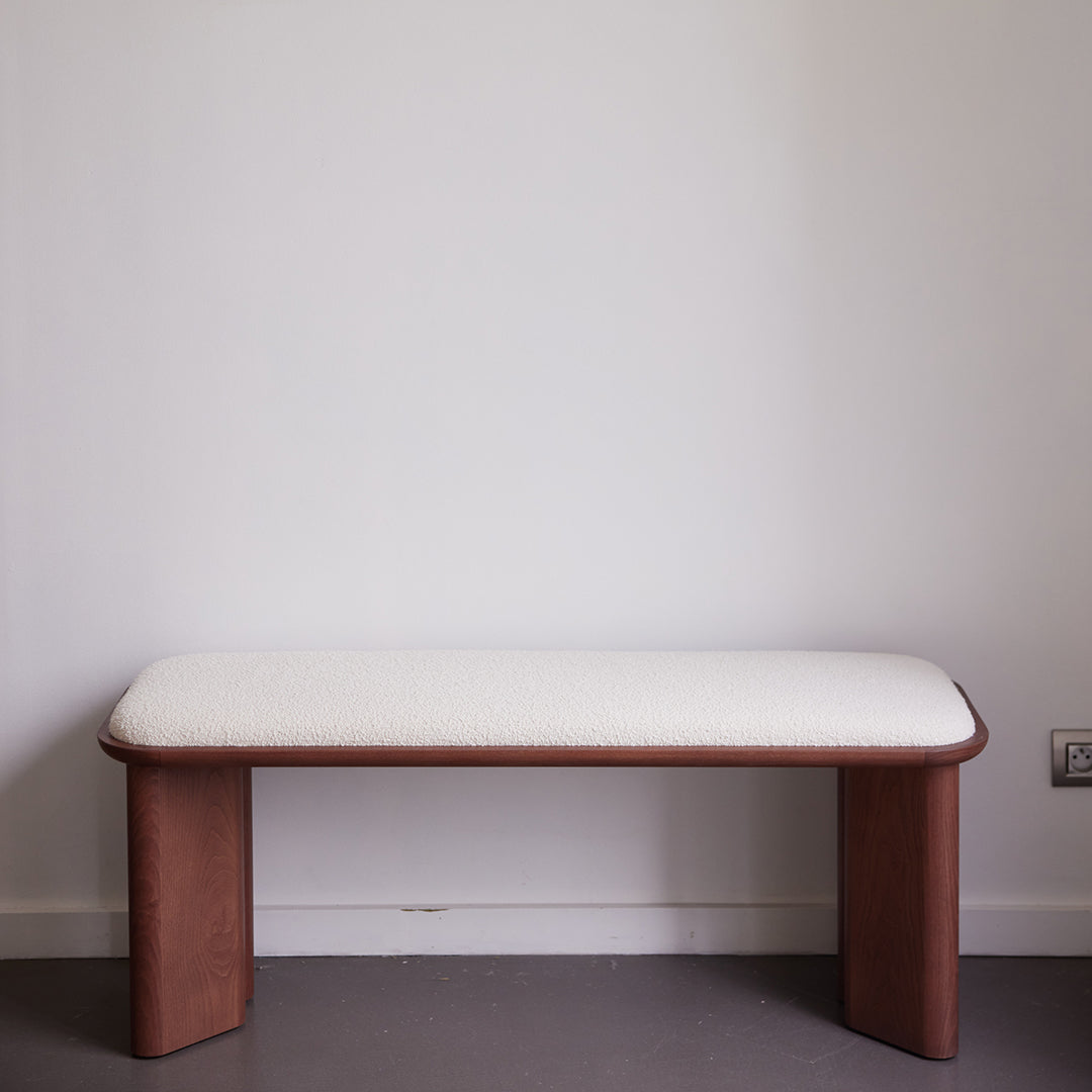 "Minimalist wooden bench with a soft cream cushion, featuring a smooth, natural wood finish."