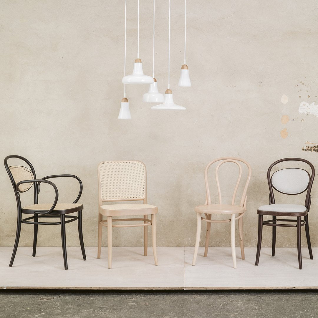 "Four stylish chairs in black, natural wood, and cream, showcasing elegant curves and minimalist design on a neutral backdrop."