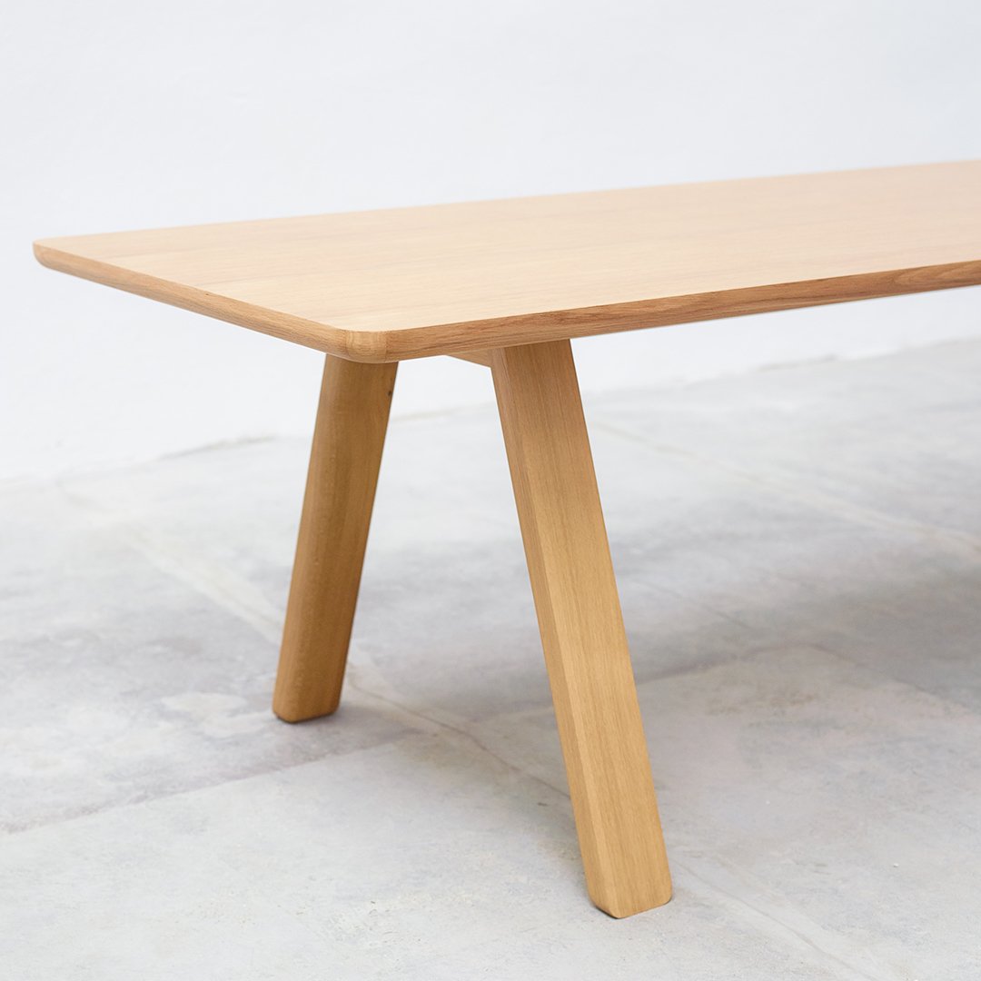 Natural light wood table with a smooth surface and tapered legs, showcasing a minimalist design.