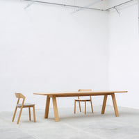 Elegant wooden dining table and chair set in natural oak finish, featuring clean lines and a minimalist design.