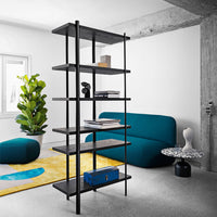 Modern black shelving unit with dark wood shelves, accented by teal couch and vibrant yellow and blue area rug.