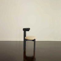 Minimalist black chair with a cream-colored cushion, featuring clean lines and no patterns. Perfect for modern spaces.