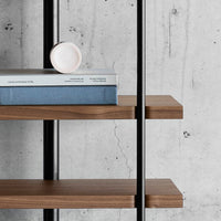 Wooden shelves with rich brown tones, complemented by light blue and soft pink accents against a gray concrete background.