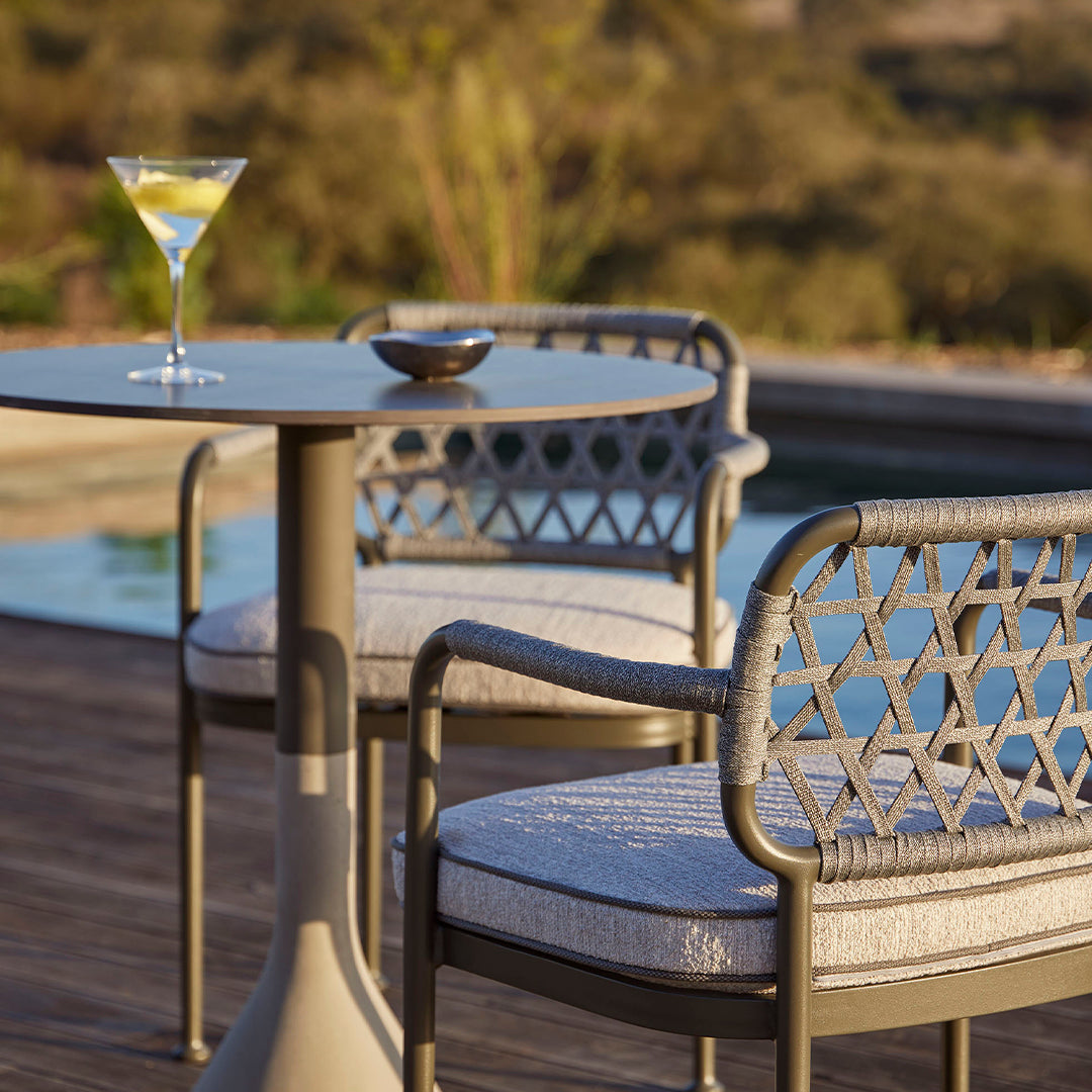"Neutral-toned outdoor seating set with geometric patterns against a vibrant natural backdrop."