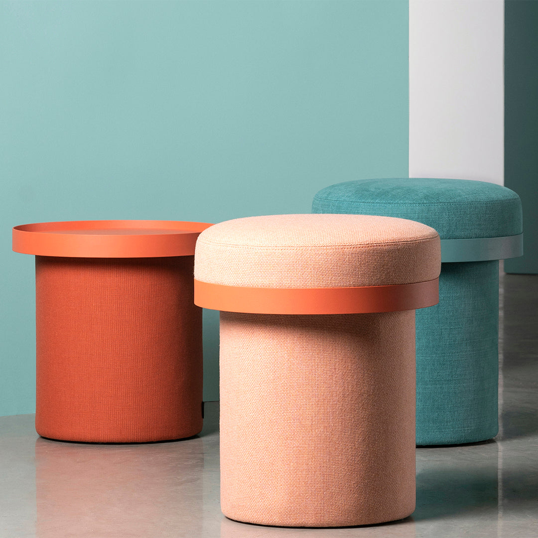 Colorful round stools in coral, peach, and teal with contrasting circular metal tops against a muted backdrop.