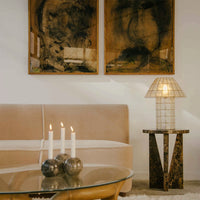 Beige sofa with abstract brown artwork, cream candles, and a geometric marble table. Soft, warm tones with texture.