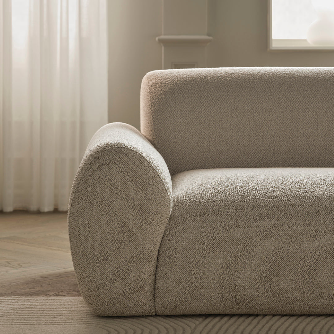 Textured light beige sofa with soft curves and subtle patterns, enhancing modern interior decor.