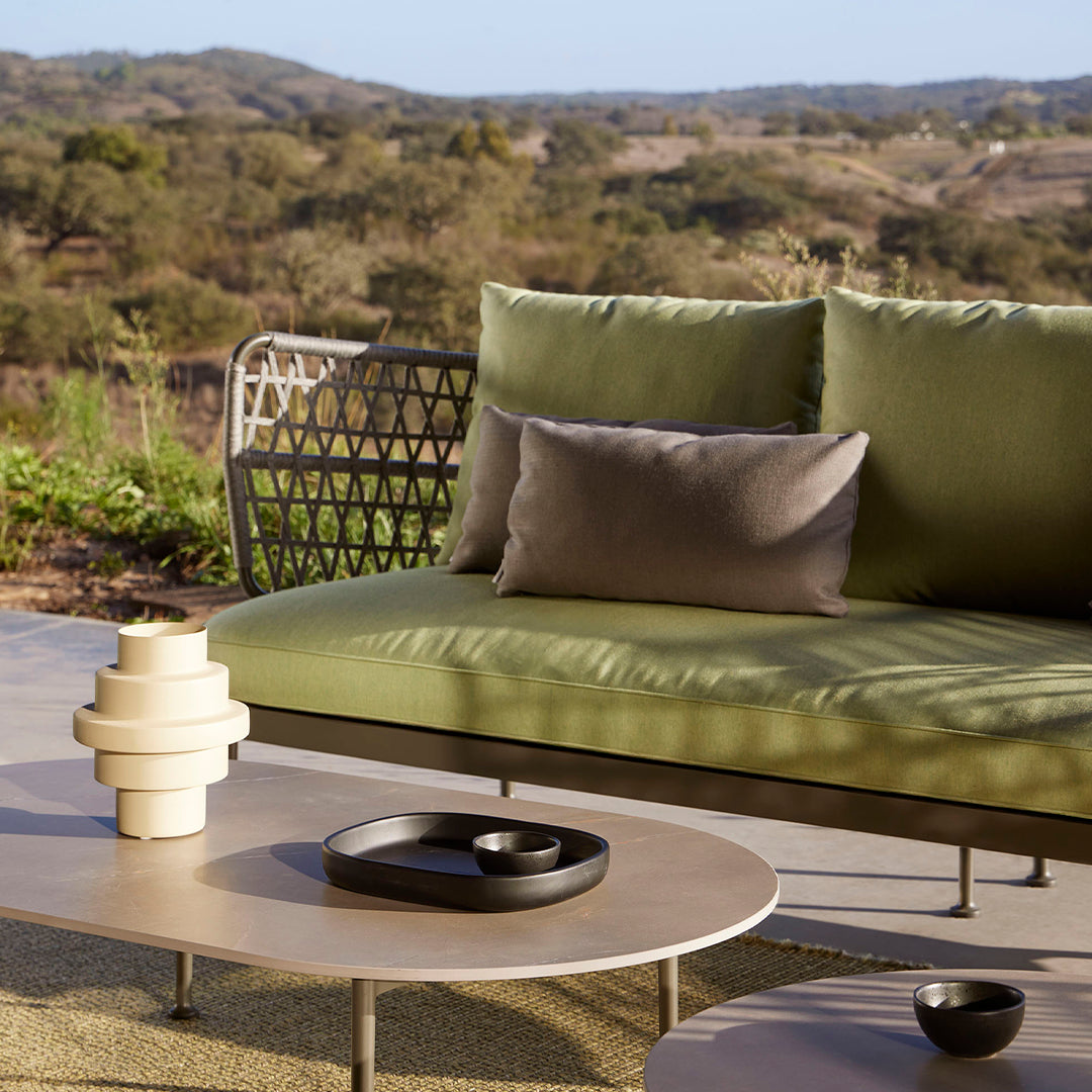 Stylish outdoor seating featuring green and gray cushions with modern patterns, complemented by black and cream accessories.