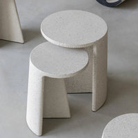 "Light gray speckled stone nesting tables with minimalist round and angular designs."