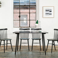 Black wooden table and chairs with a minimalist design, featuring a light blue patterned seat cushion against a neutral backdrop.