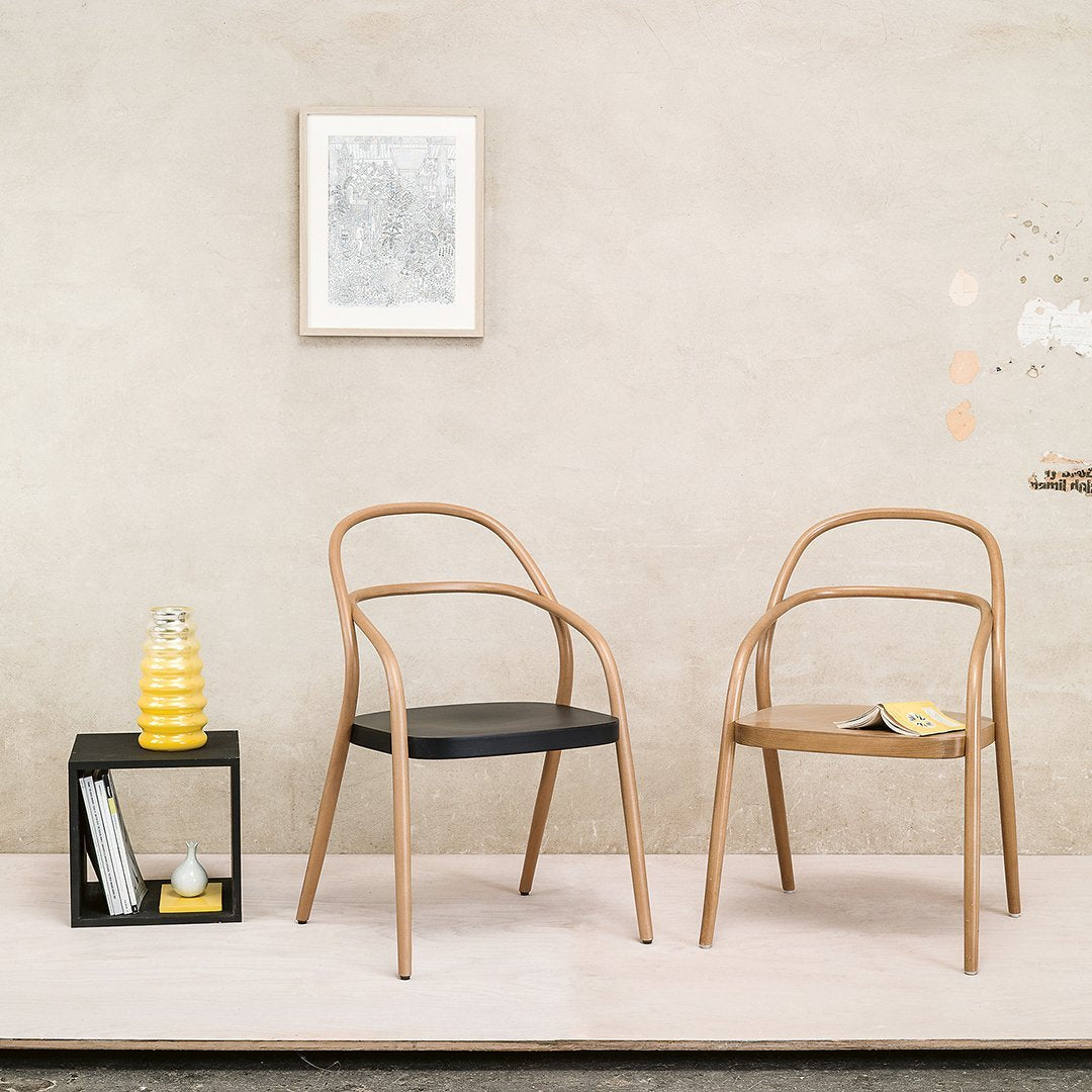Light wood frame chairs with black and natural wood seats, set against a neutral, textured wall background.