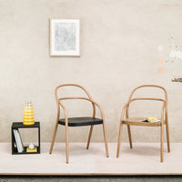 Light wood frame chairs with black and natural wood seats, set against a neutral, textured wall background.