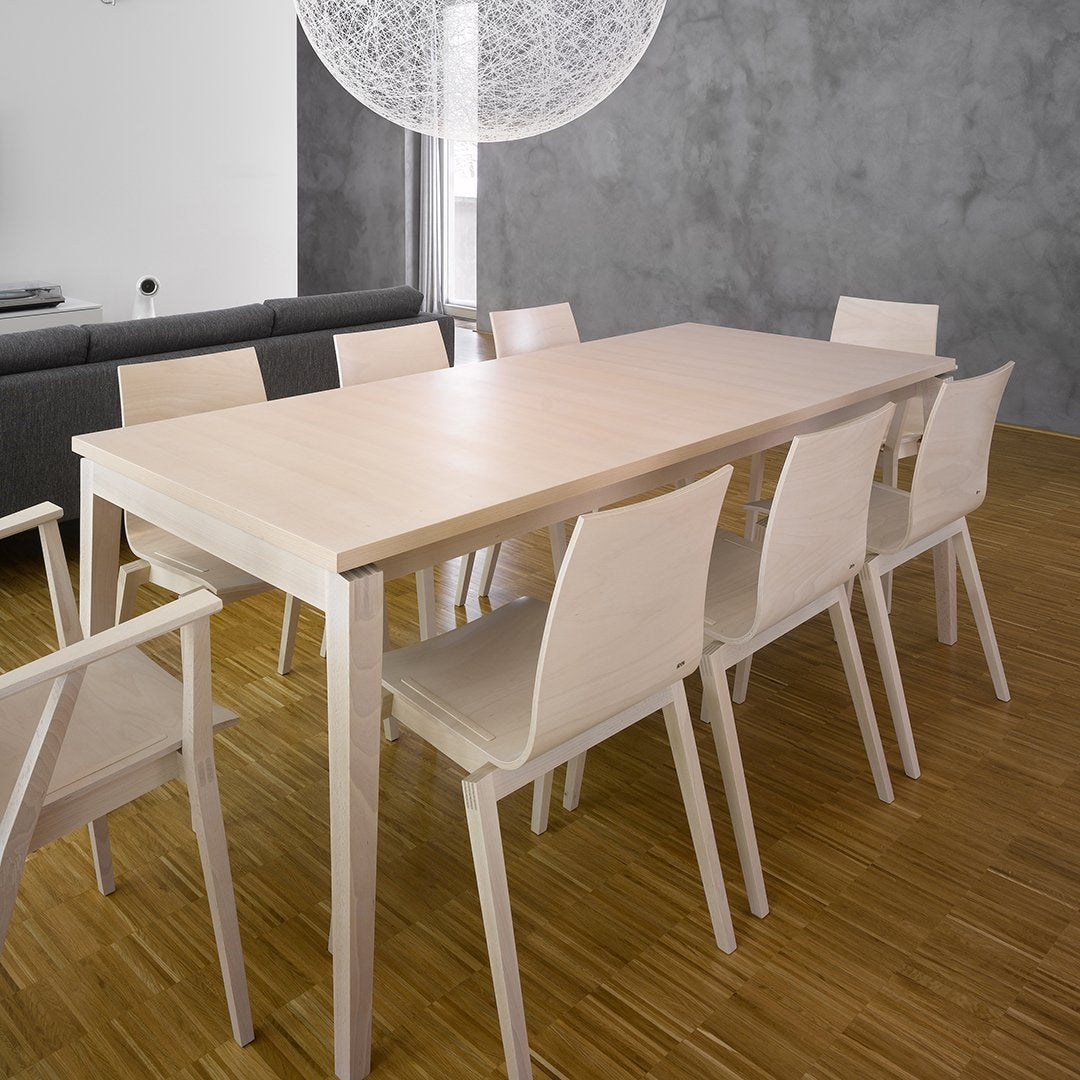 Light wood dining table with matching chairs, set against a gray wall and bamboo flooring for a modern, minimalist aesthetic.