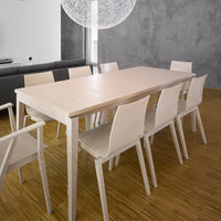 Light wood dining table with matching chairs, set against a gray wall and bamboo flooring for a modern, minimalist aesthetic.