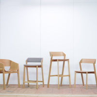 "Light wood chairs with minimalist design; features natural finishes and a grey upholstered seat."