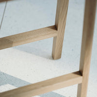Light oak wooden chair legs with a natural finish against a speckled white background.