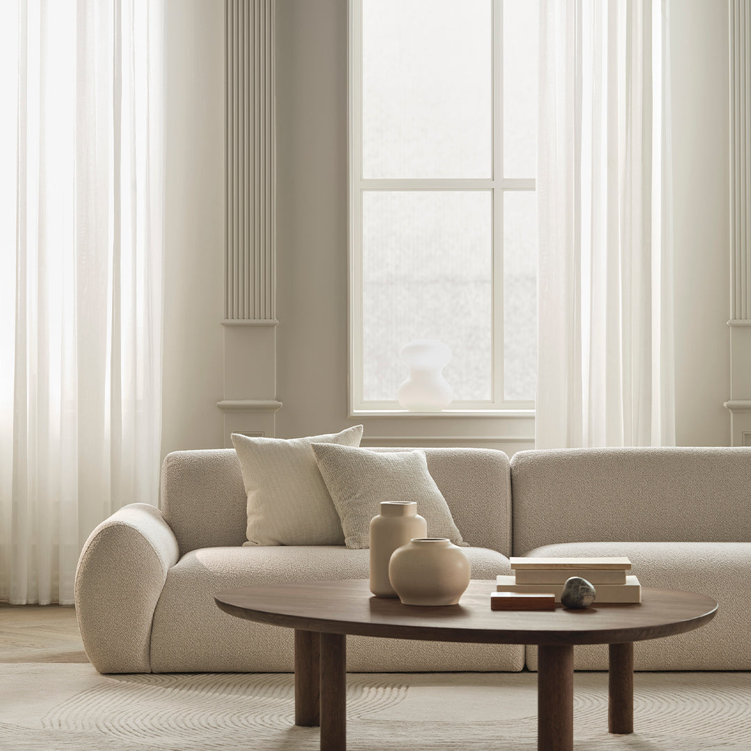 Textured beige sofa with neutral pillows, paired with a wooden coffee table and soft, light-colored decor accents.