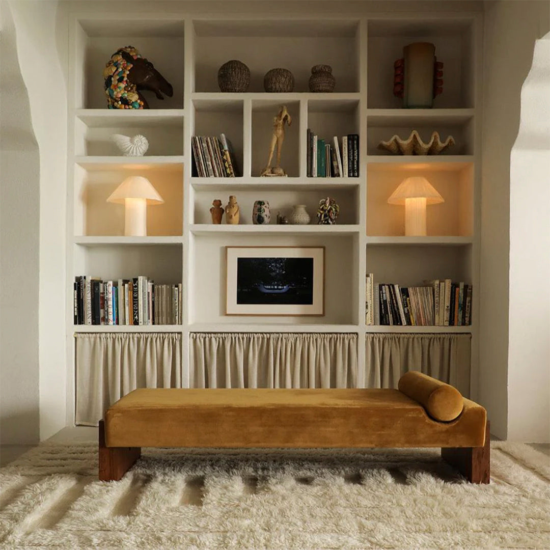 "Modern decor featuring neutral tones, warm yellow, soft textures, and earthy patterns in a stylish bookshelf setting."
