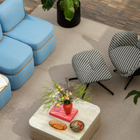 Blue sectional sofa with orange trim, black and white zigzag chairs, pink decor, and green foliage accents.