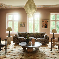Zebra-patterned black and white couch in a pastel pink room with earthy tones from the rug and decor elements.
