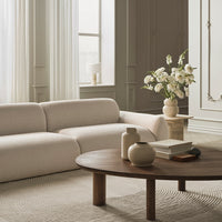 Beige sofa with textured fabric, light wooden coffee table, neutral tones, and soft white floral arrangement.