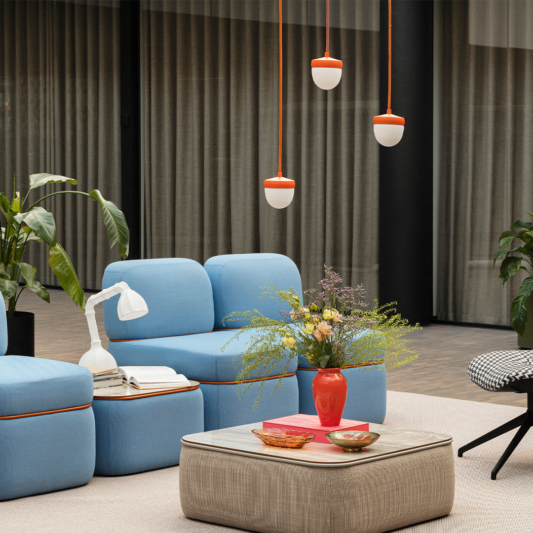 Blue seating with orange accents, green plants, and warm hues from floral arrangements and decorative items.